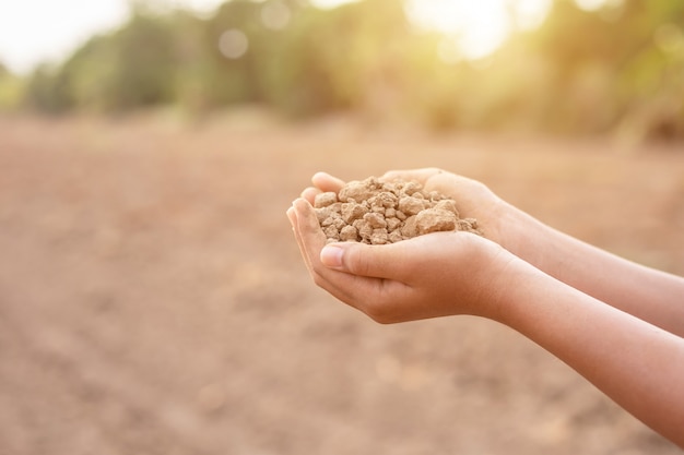 Giovane agricoltore che tiene terreno asciutto in terra vuota per piantare