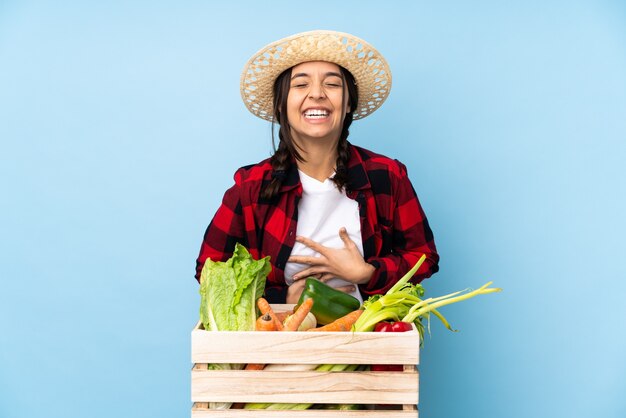 Giovane agricoltore Donna che tiene la verdura fresca in un cestino di legno che sorride molto