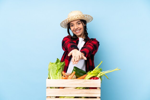 Giovane agricoltore Donna che tiene la verdura fresca in un cestino di legno che tiene il copyspace immaginario sul palmo per inserire un annuncio