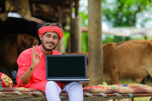 Giovane agricoltore indiano che mostra un computer portatile