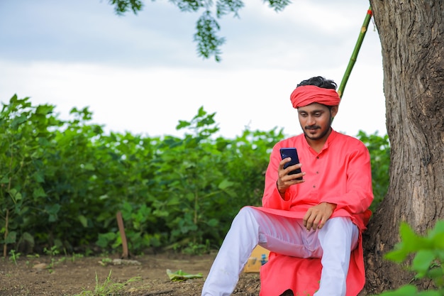 Giovane agricoltore indiano che utilizza il telefono