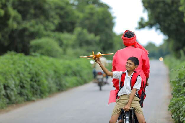 Giovane agricoltore indiano con suo figlio in bicicletta