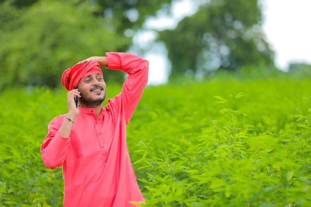 Giovane agricoltore indiano parlando al telefono cellulare in un campo