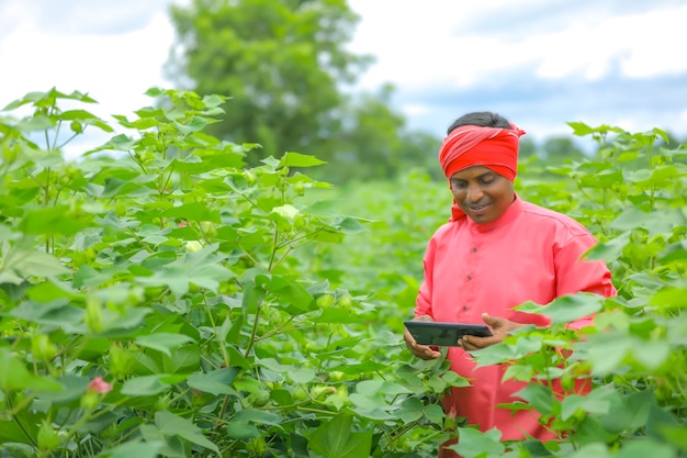 Giovane agricoltore indiano utilizzando il telefono cellulare al campo agricolo