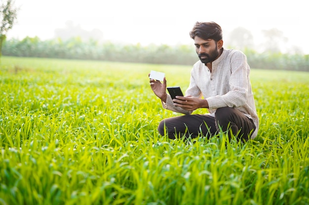 Giovane agricoltore indiano utilizzando uno smart phone