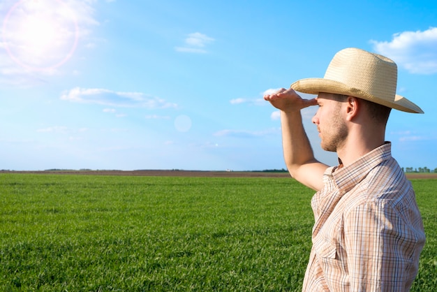 Giovane agricoltore nel campo osservando i raccolti.