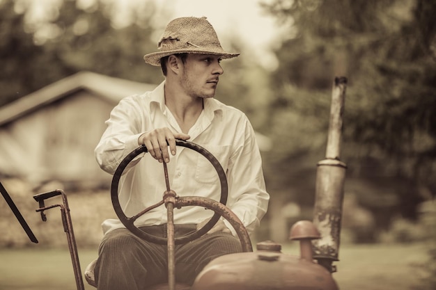 Giovane agricoltore su un trattore d'epoca