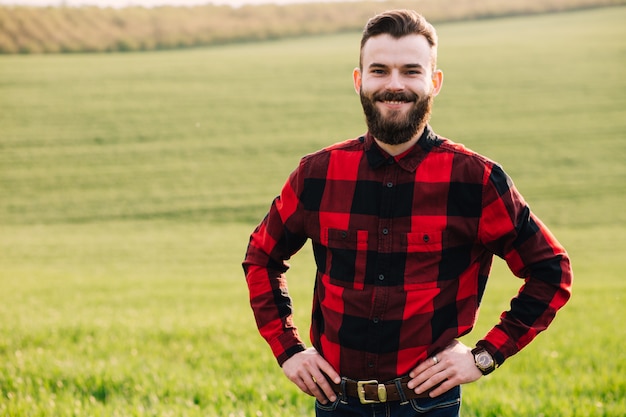 Giovane agronomo barbuto che sta nel campo coltivato del raccolto del grano