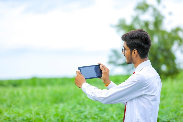 Giovane agronomo indiano che mostra smartphone al campo