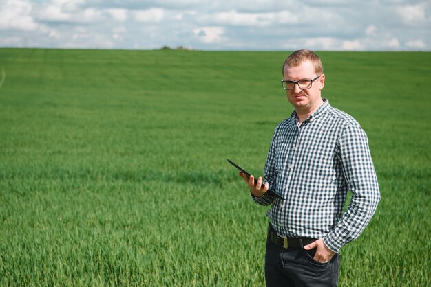 Giovane agronomo tiene tablet touch pad computer nel campo di grano verde