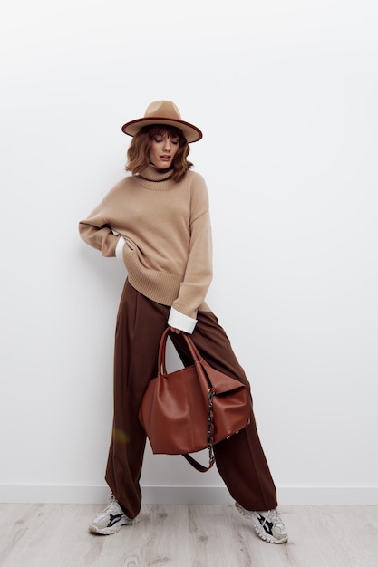 Giovane alla moda con la borsa in piedi contro il muro bianco