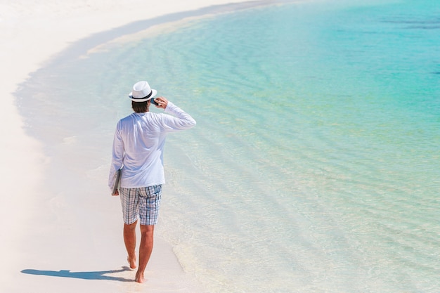 Giovane alla spiaggia tropicale vicino alla villa sull'acqua