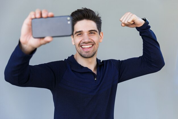 Giovane allegro che cattura un selfie isolato sopra gray