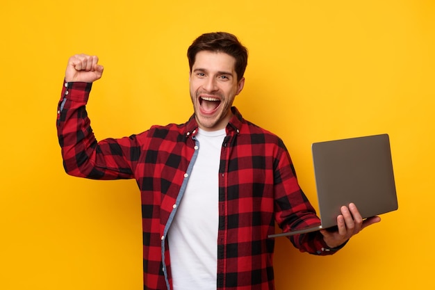 Giovane allegro che per mezzo del computer portatile che gesturing sì