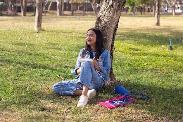 Giovane allegro seduto nel parco che disegna giacca e jeans Picturewears Concetto di vita cittadina