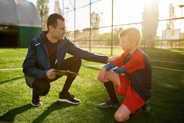 Giovane allenatore di calcio che dà supporto al piccolo calciatore