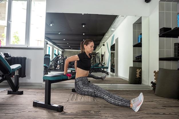 Giovane allenatore femminile si allena in palestra per ottenere la figura dei suoi sogni Una donna attraente con un corpo muscoloso si allena in una palestra moderna e luminosa Esecuzione di esercizi