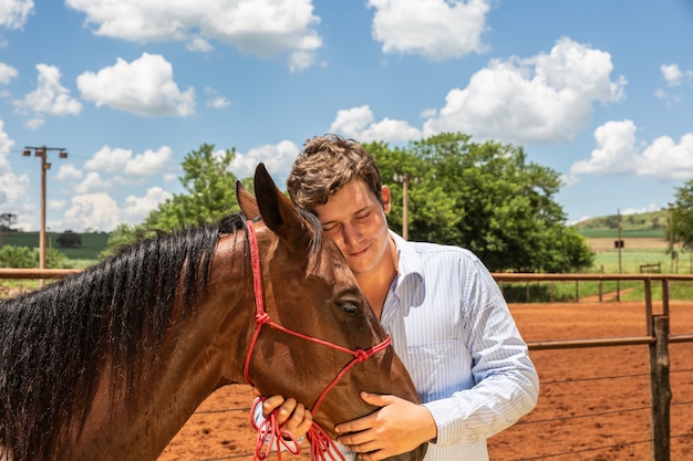 Giovane allevatore di cavalli che conforta un cavallo nel ranch