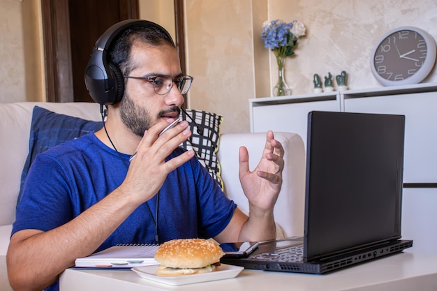 Giovane arabo che mangia mentre lavora ea casa