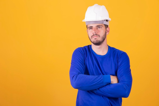 Giovane architetto con casco con le braccia incrociate con spazio libero per il testo