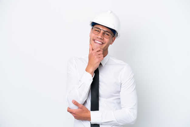 Giovane architetto uomo caucasico con casco e azienda progetti isolati su sfondo bianco felice e sorridente