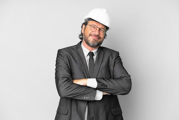 Giovane architetto uomo con casco su sfondo isolato mantenendo le braccia incrociate in posizione frontale