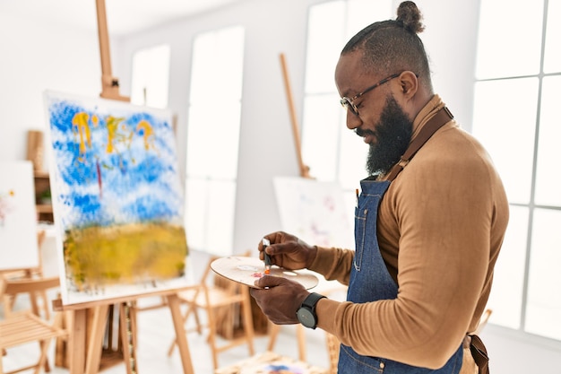 Giovane artista afroamericano uomo sorridente disegno felice presso studio d'arte.