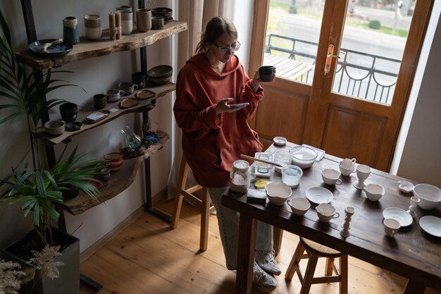 Giovane artista artigianale che promuove il business della ceramica sui social media lavorando in un accogliente studio di ceramica