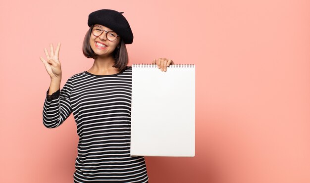 giovane artista donna sorridente e guardando amichevole, mostrando il numero quattro o quarto con la mano in avanti, il conto alla rovescia