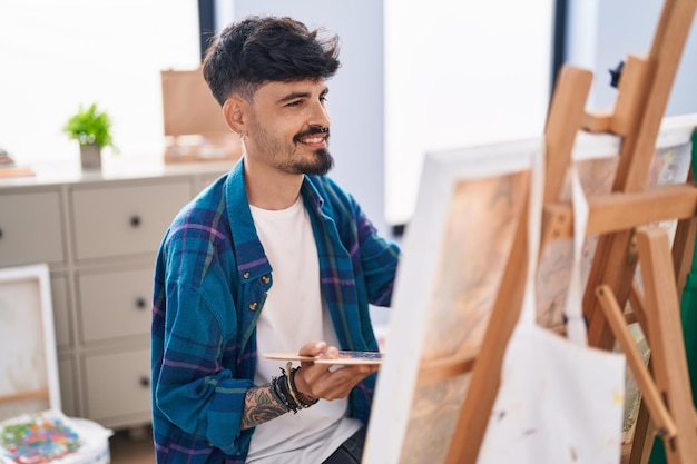 Giovane artista ispanico sorridente disegno fiducioso presso studio d'arte