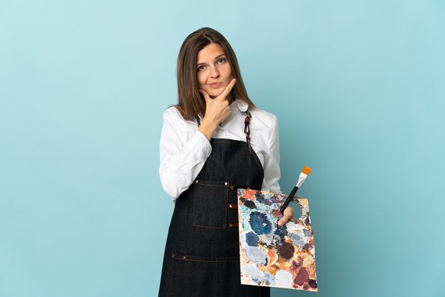 Giovane artista slovacco donna isolata su sfondo blu pensando