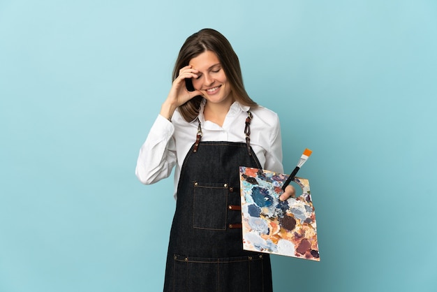 Giovane artista slovacco donna isolata su sfondo blu ridendo