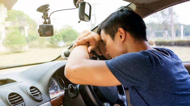 Giovane asiatico che dorme nella sua auto.