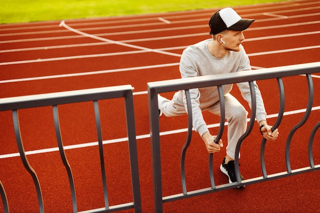 Giovane atleta che riposa dopo aver corso nello stadio in estate