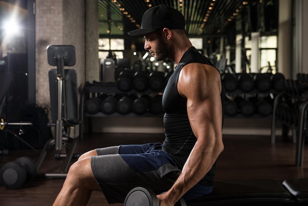 Giovane atleta in palestra che esegue curl bicipiti con manubri