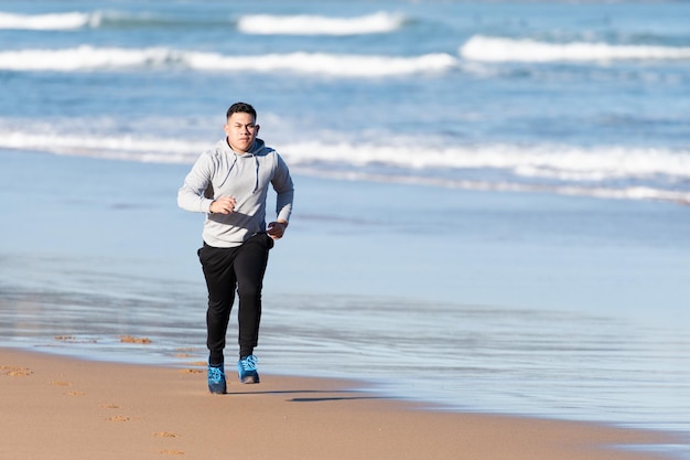 Giovane atleta latino motivato e concentrato che si allena al mare