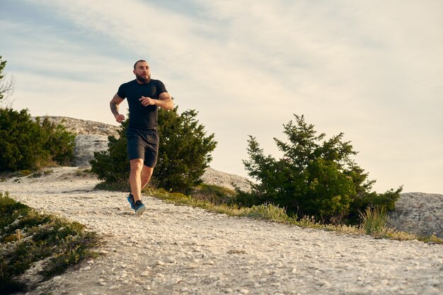 Giovane atleta maschio muscoloso che corre su per la collina