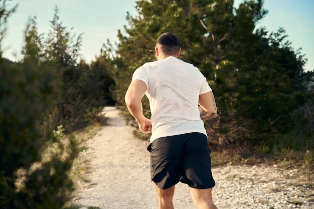 Giovane atleta maschio muscoloso che corre su per la collina