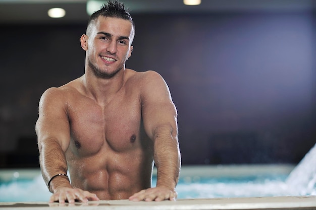 Giovane atleta modello uomo macho dall'aspetto sano e bello presso la piscina interna dell'hotel