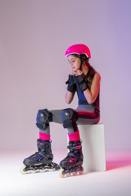 giovane atleta pattinatore con casco rosa e equipaggiamento protettivo per la foto in studio della competizione