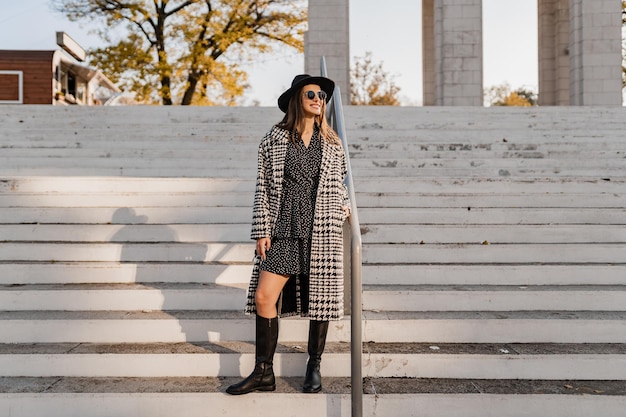 Giovane attraente che cammina in autunno con il cappotto.