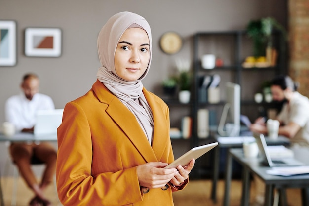 Giovane azienda leader femminile in hijab con tablet in mano guardando la fotocamera