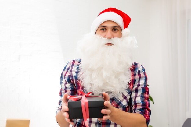 giovane Babbo Natale che tiene i regali su sfondo bianco