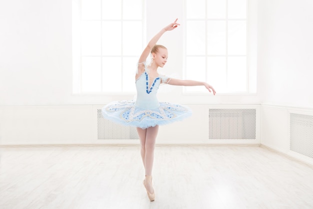 Giovane ballerina dell'adolescente che pratica il passo di danza classica in studio prima della performance. Studente di balletto che si esercita in costume di balletto, in piedi sulle punte dei piedi.