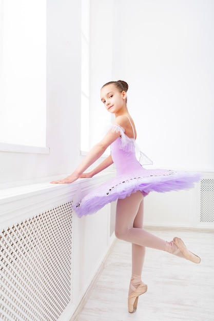 Giovane ballerina dell'adolescente che pratica il passo di danza classica in studio prima della performance. Studente di balletto che si esercita in costume di balletto, in piedi sulle punte dei piedi.