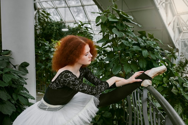 Giovane ballerina femminile che balla in un giardino botanico al chiuso