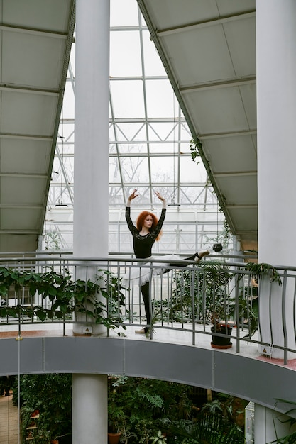 Giovane ballerina femminile che balla in un giardino botanico al chiuso