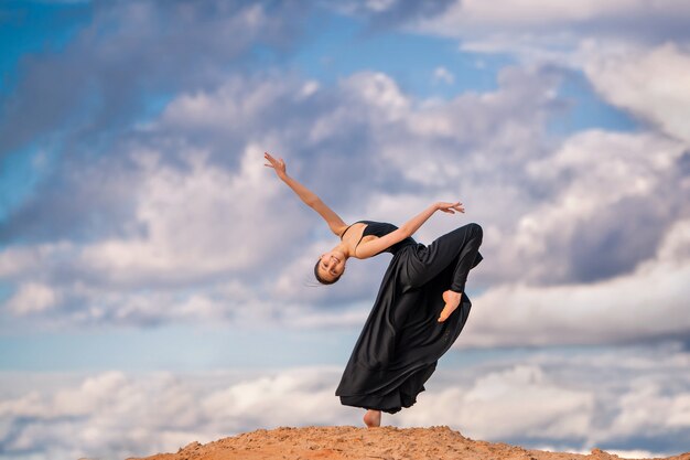 Giovane ballerina in un vestito lungo nero che balla