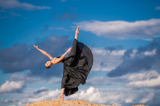 Giovane ballerina in un vestito lungo nero che balla