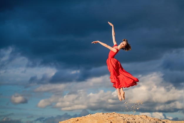 Giovane ballerina in un vestito lungo rosso che balla